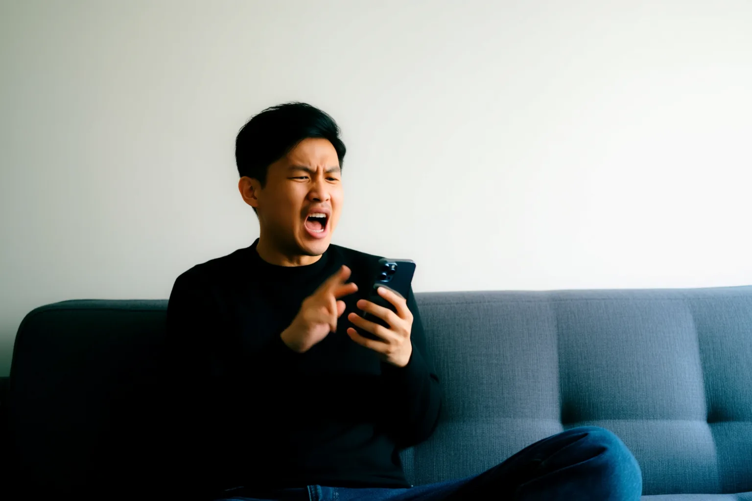 Eine Person spricht laut ins Smartphone auf dem Sofa, während eine KI-Stimme antwortet und korrigiert.