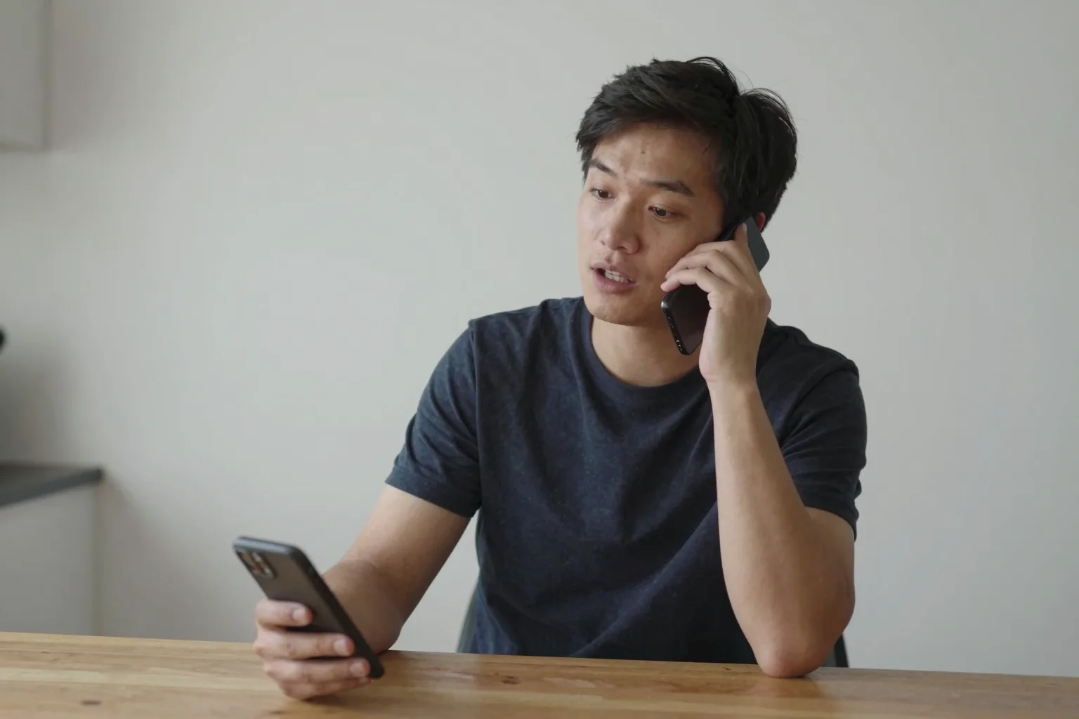 Person speaking Spanish name exchange into phone, relaxed at a kitchen table.
